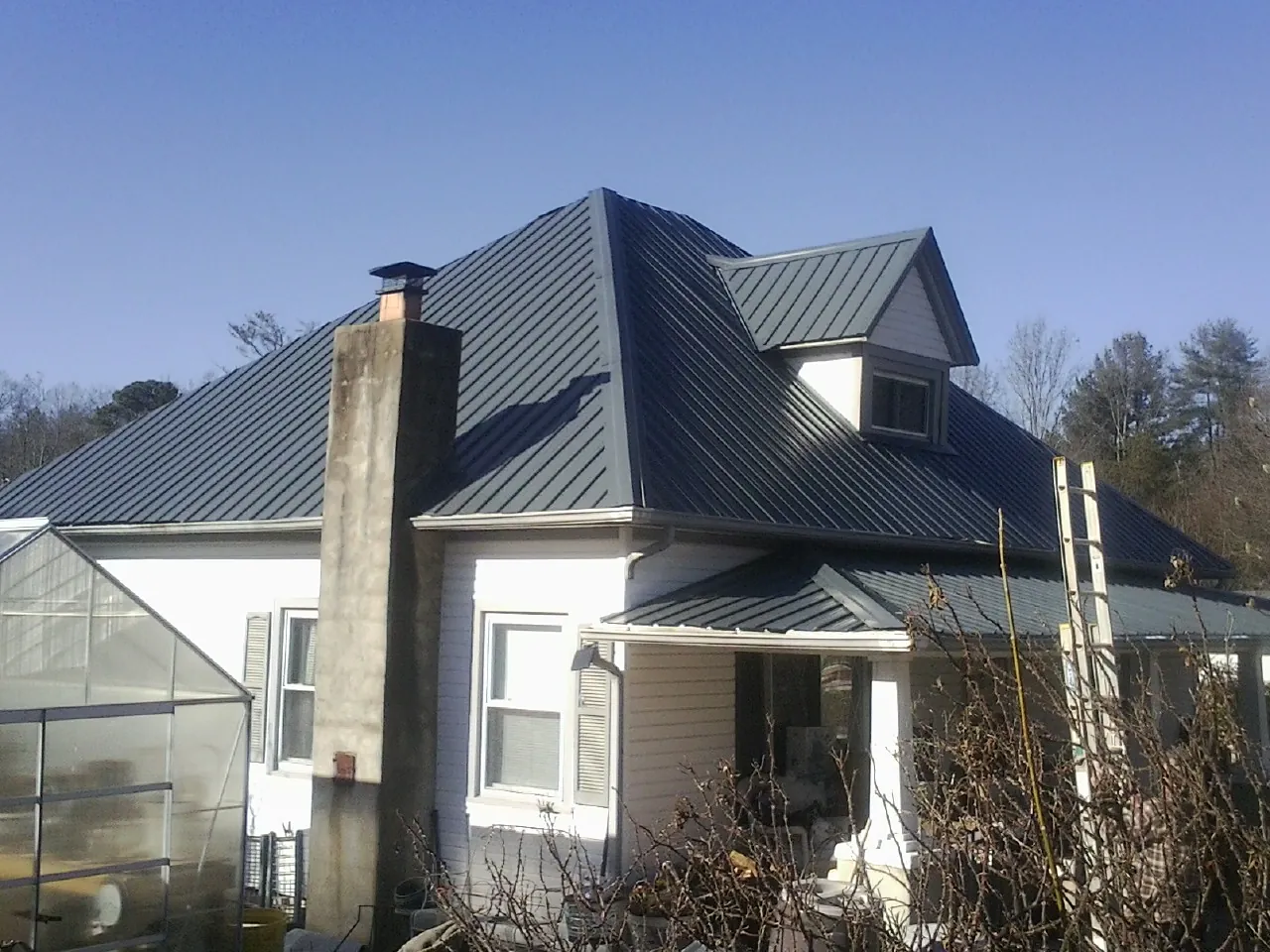 Dark blue standing seam metal roof on a white farmhouse with dormer — Slate & Tile Roof Repair by Roofing Brothers in Savanna