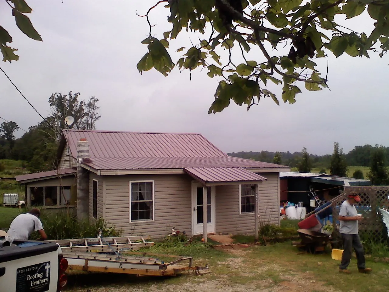 Crew finishing a mauve metal roof on a small farmhouse in Savanna