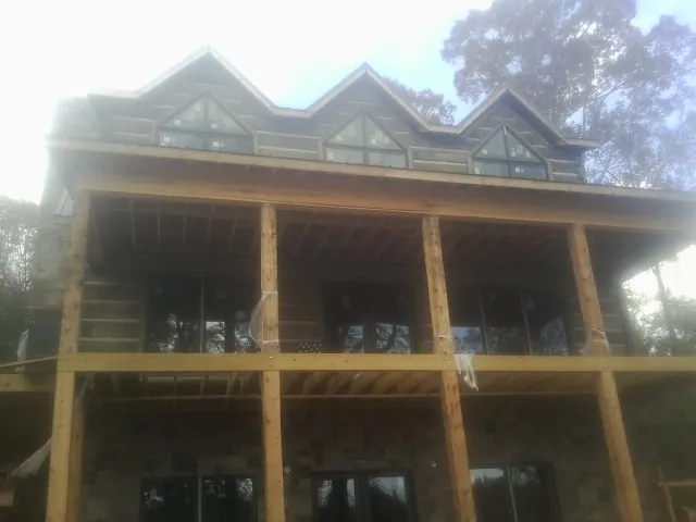 Dormers and porch framing on a large log home under construction — Roof Coating work by our crew in Savanna
