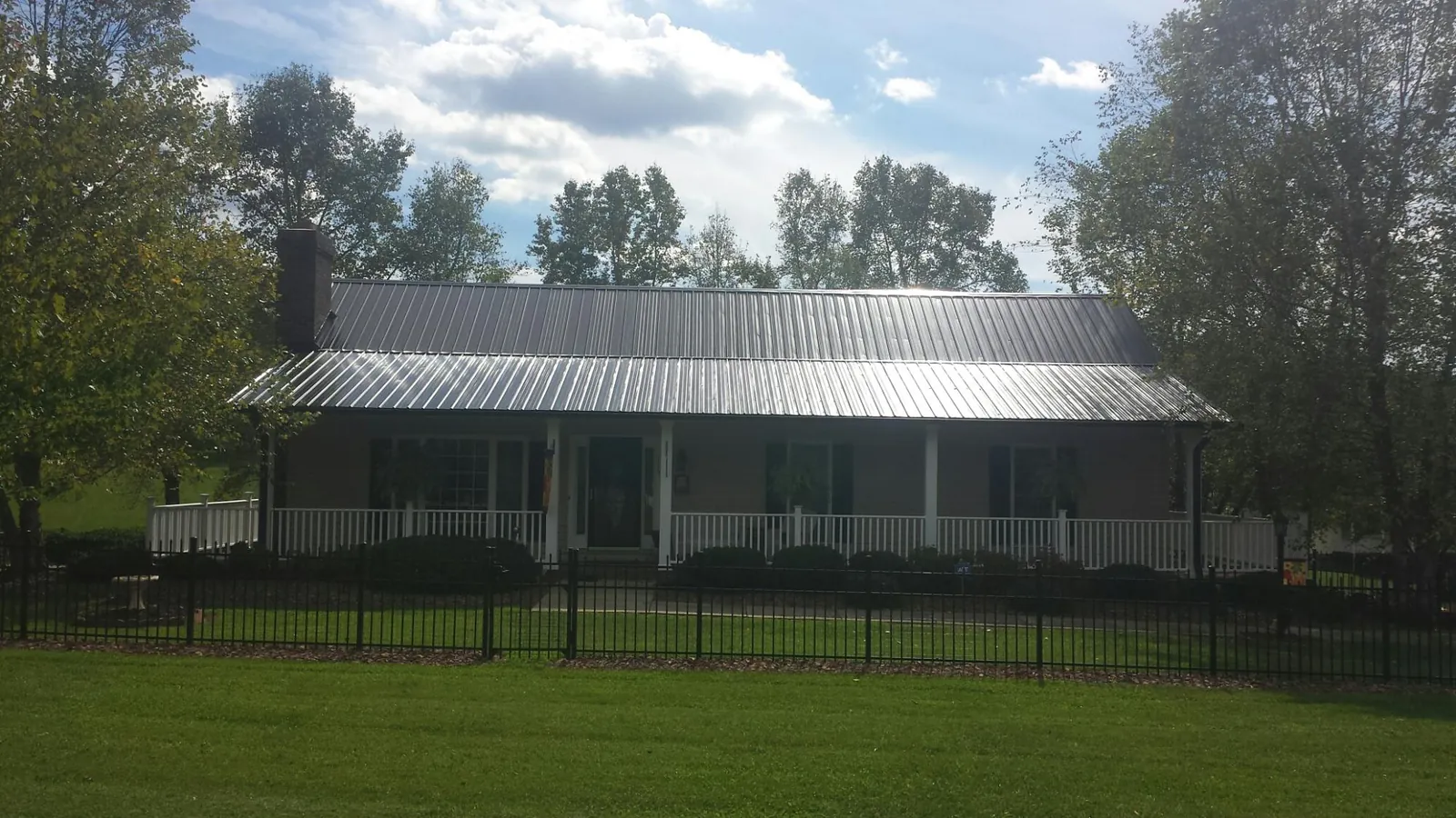 Gray metal roof on a brick ranch with a full width front porch — Gutter Guard Installation work by our crew in Savanna