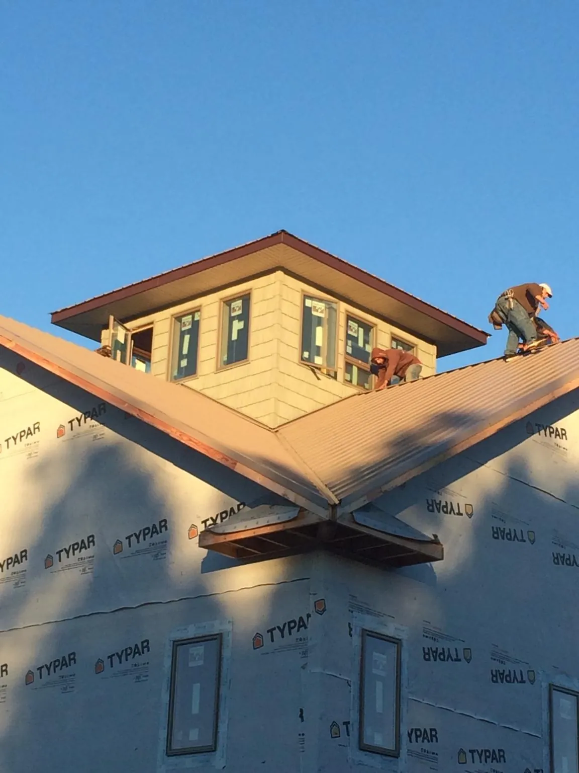 Roofers working around a rooftop cupola on a new metal roof at sunset — Roof Waterproofing in Savanna by Roofing Brothers